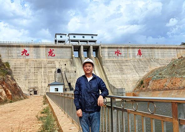 王龙在九龙水库大坝前留影。何晓超 摄.jpg